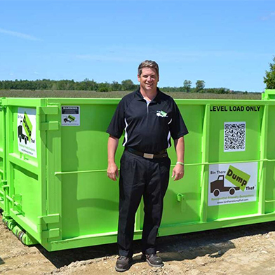 A Bin There Dump That operator stands in front of a 14 yard dumpster bin