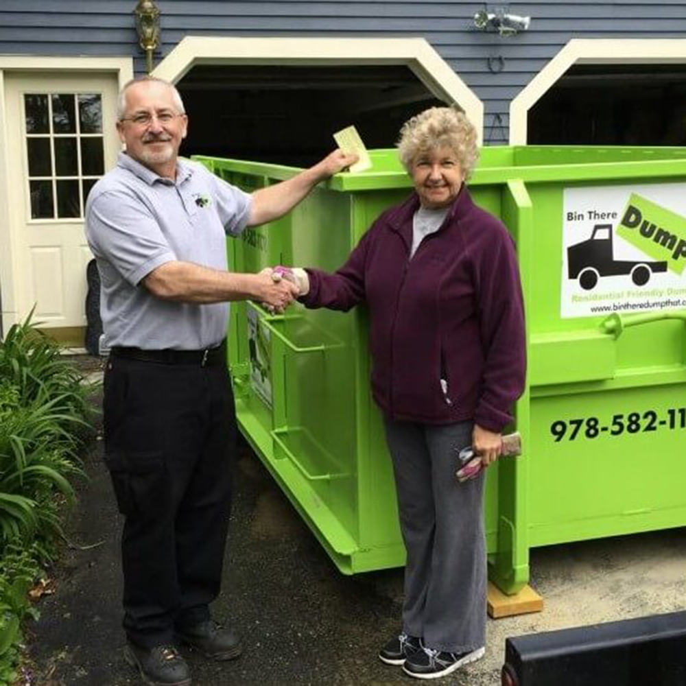 A Franchise Operator shakes the hand of a customer in front of a Bin There Dump That dumpster bin