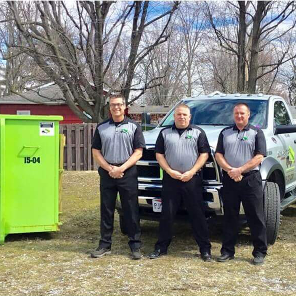 Franchise Operators stand in front of a Bin There Dump That truck and dumpster bin
