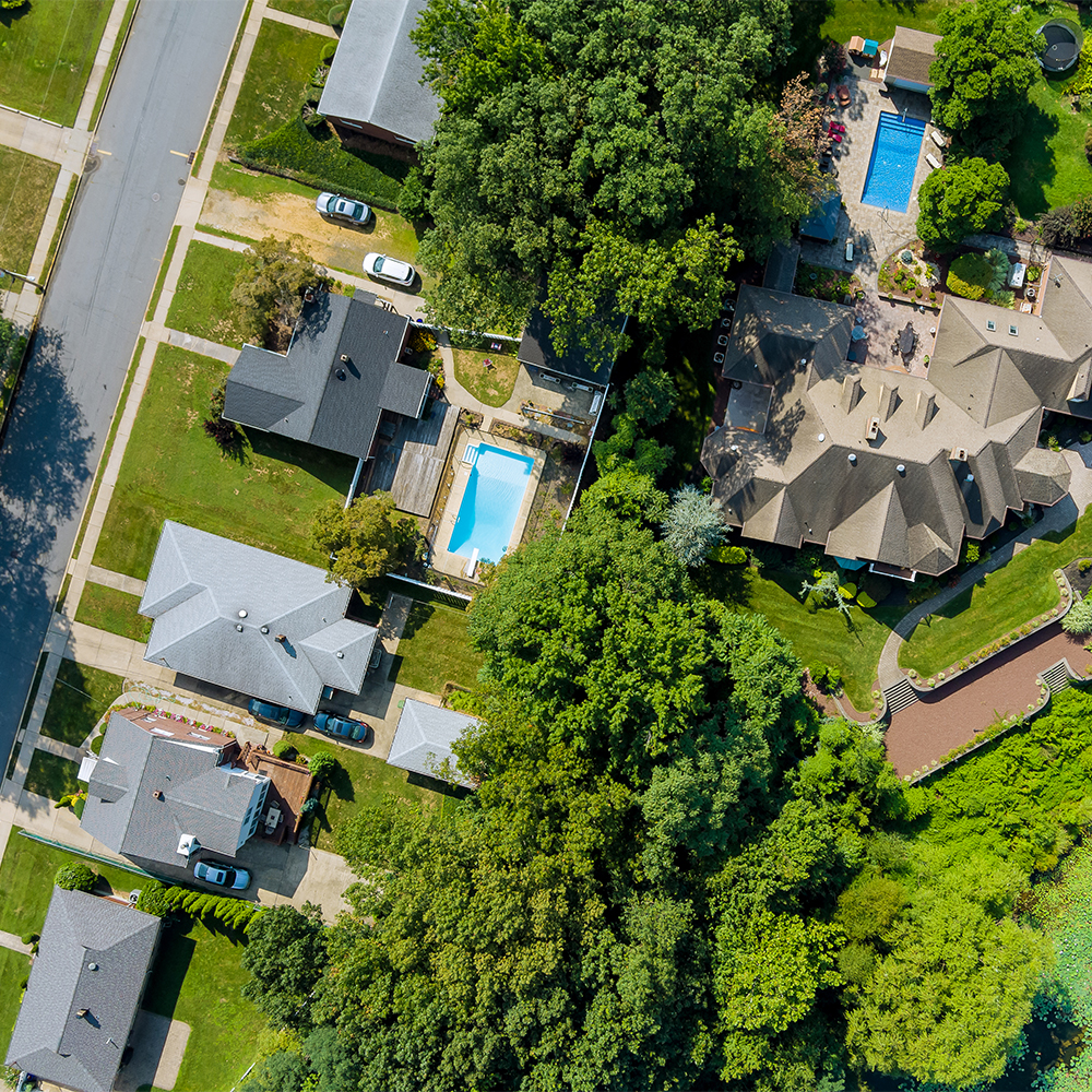A quiet suburban neighborhood, neatly arranged with houses, green lawns, and mature trees.
